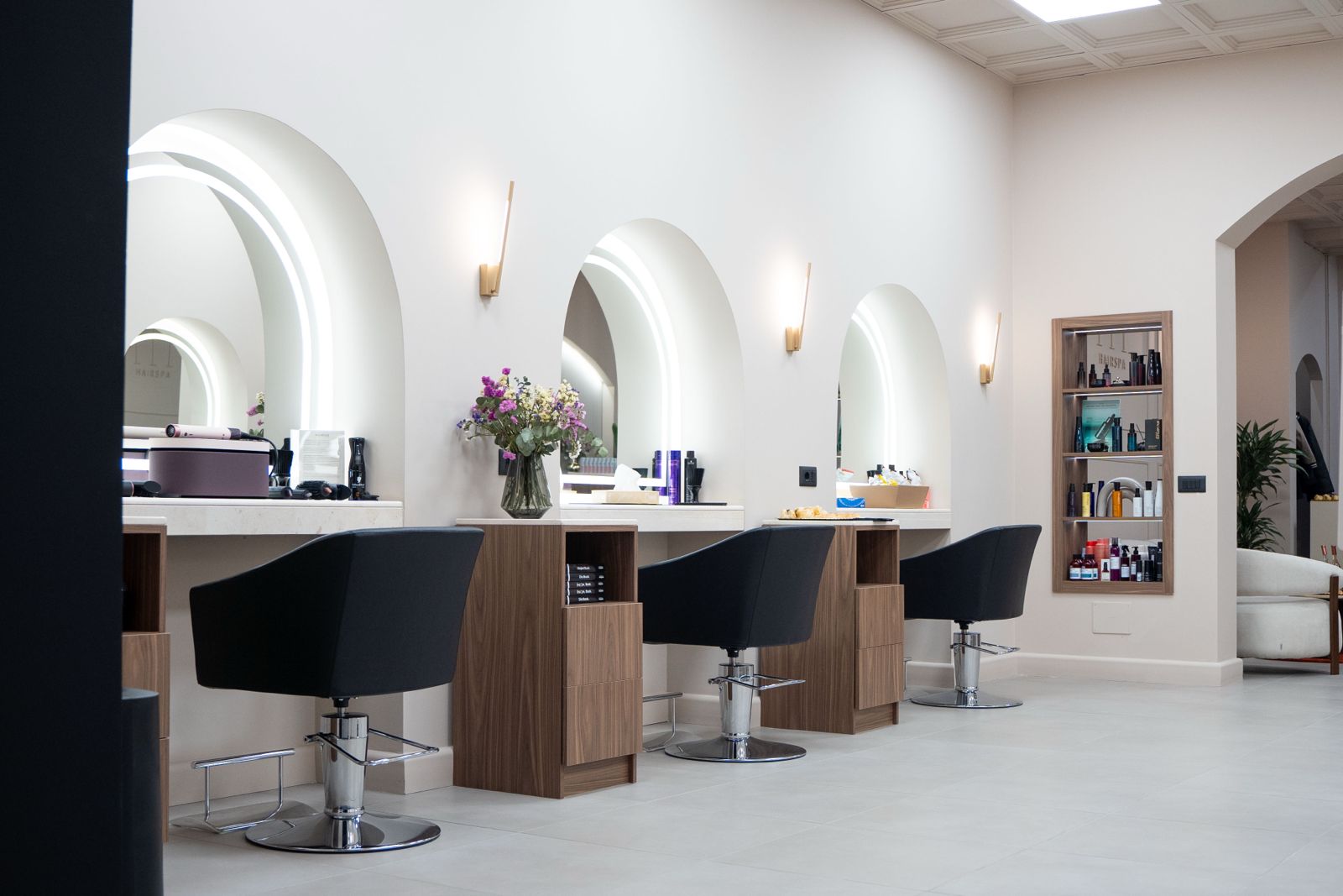 Salon de coiffure aménagé par DH Salon Design — postes avec arches et fauteuils noirs